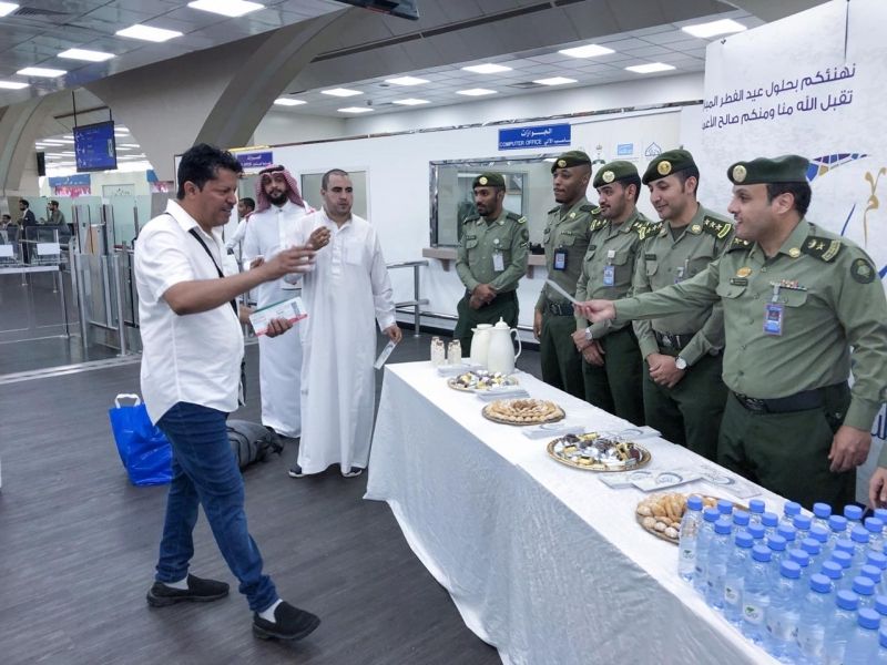 شاهد بالصور.. جوازات مطار الملك عبدالعزيز تعايد المسافرين بالحلوى والهدايا