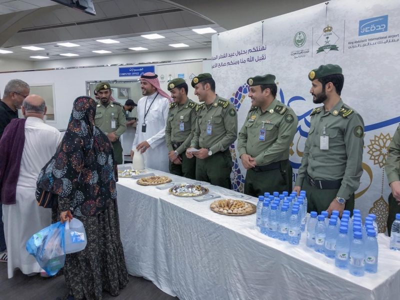 شاهد بالصور.. جوازات مطار الملك عبدالعزيز تعايد المسافرين بالحلوى والهدايا