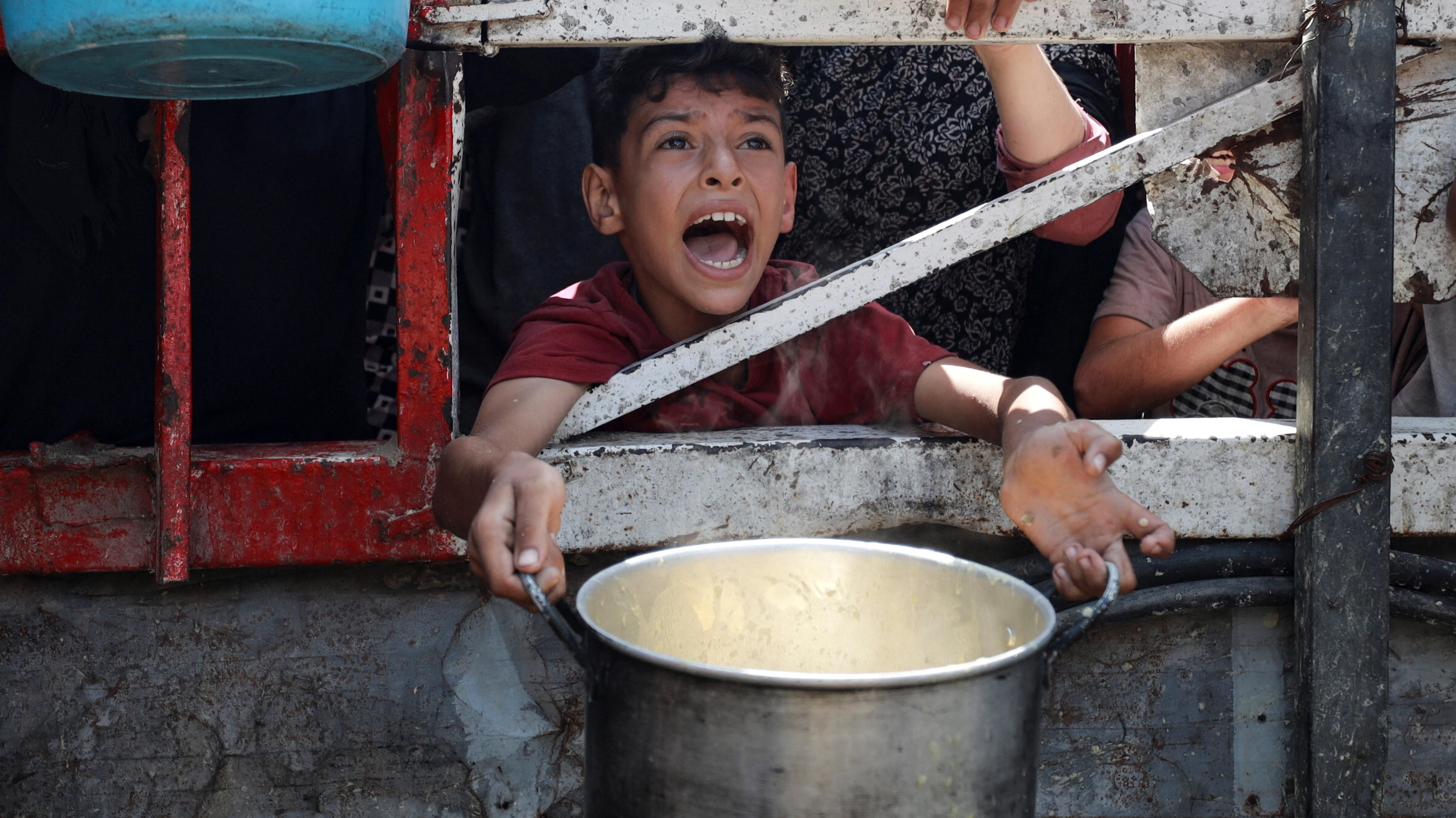 صورة تظهر فتى فلسطينياً ينتظر الحصول على طعام أمام أحد المطابخ الخيرية في مدينة غزة.